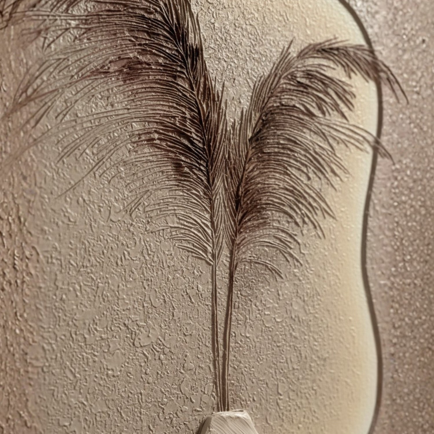 A close-up of a decorative wall hanging or textured panel featuring a stylized pampas grass motif in dark brown against a warm beige background.