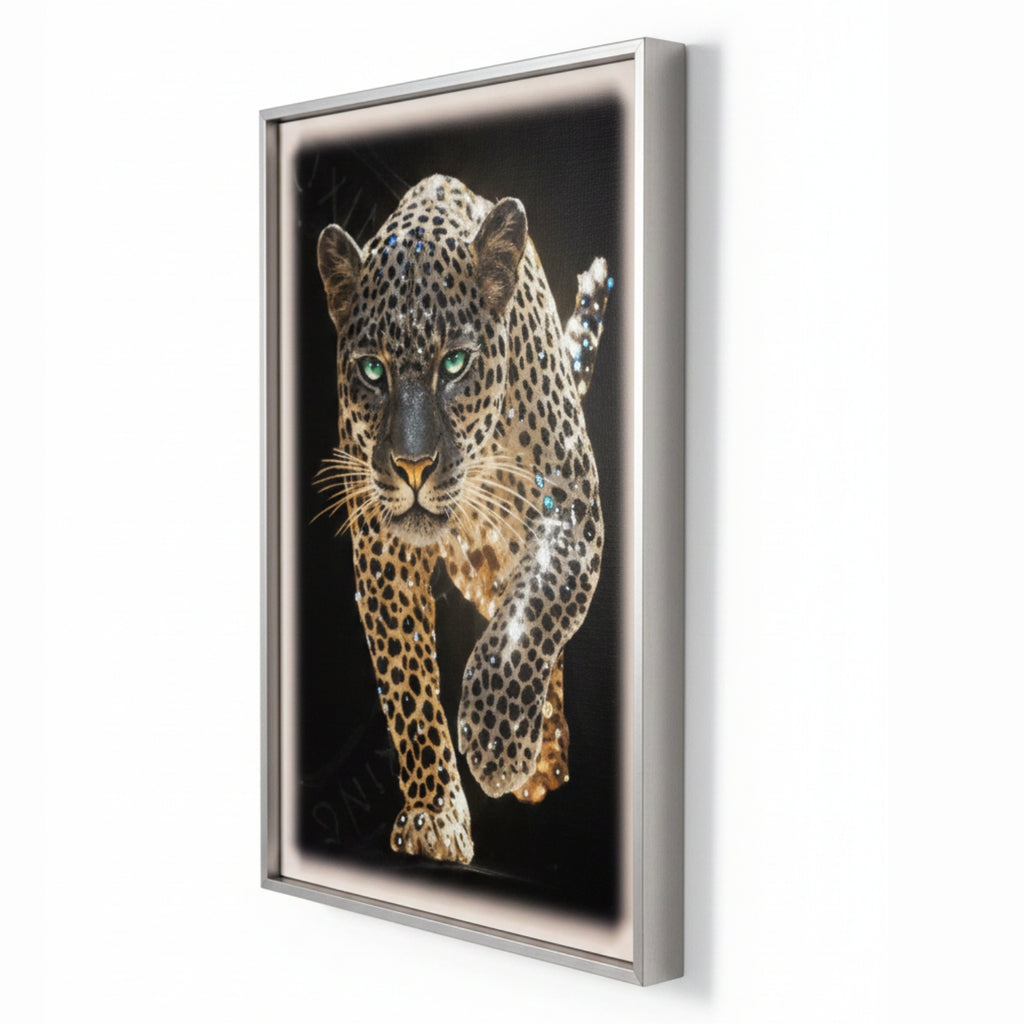 A framed wall art print featuring a detailed leopard with green eyes on a black background, shown hanging on a white wall.