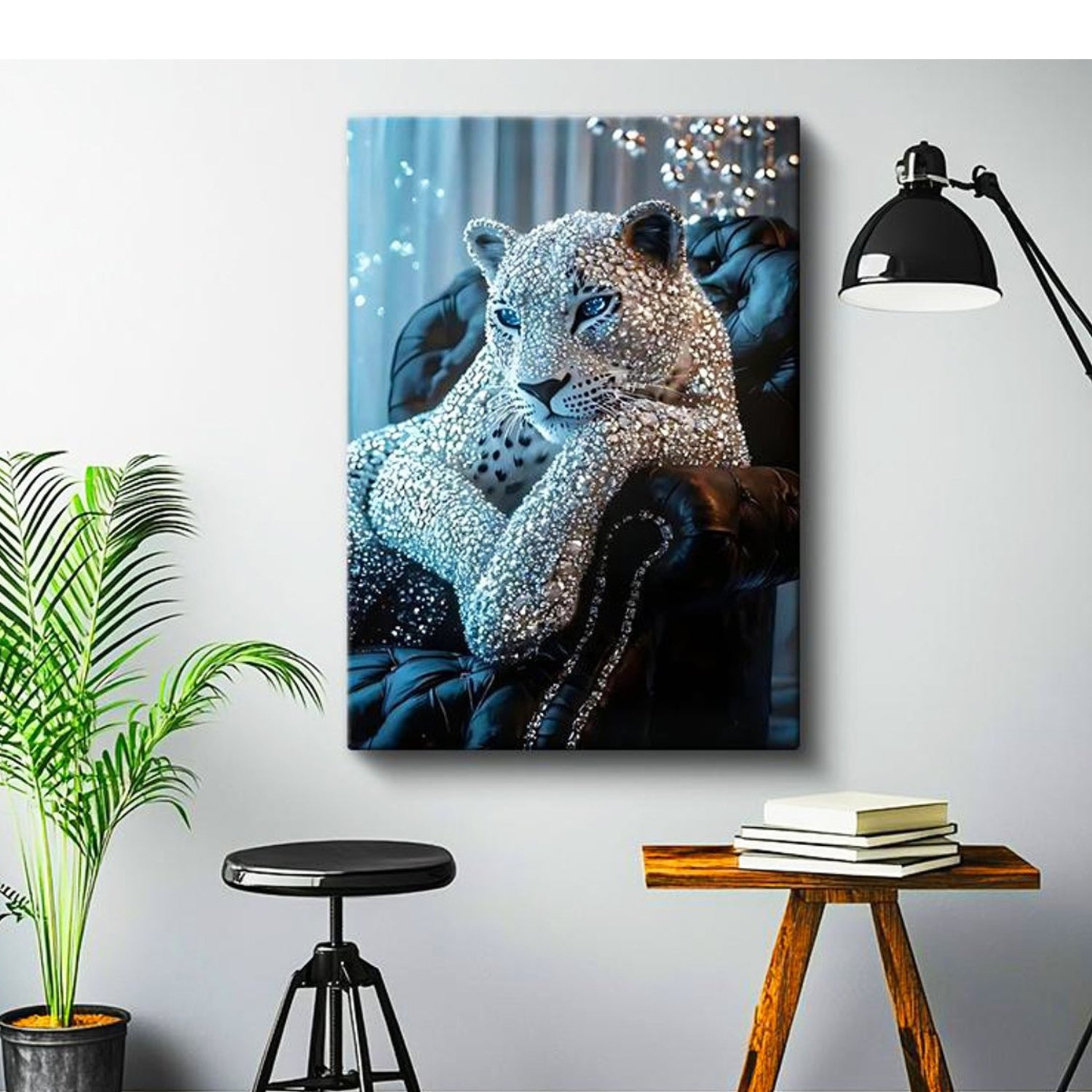A rectangular wall art print showing a leopard reclining on a dark tufted chair, styled in a modern room with a black floor lamp, a potted plant, a stool, and a small wooden side table with books.