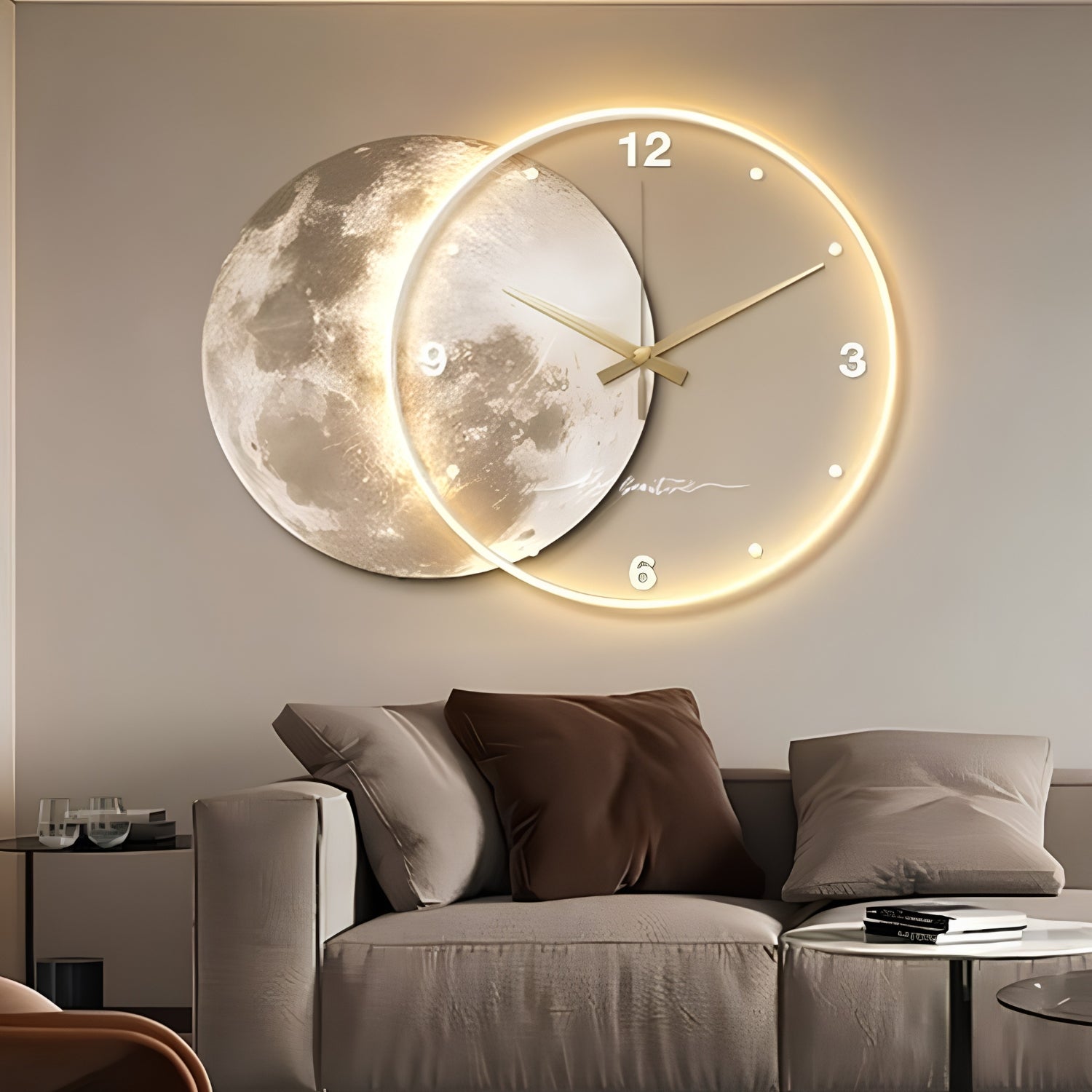 A modern wall clock mounted above a sofa in a living room. The clock features a large illuminated gold ring with a moon face design behind it and white Arabic numerals at the 12, 3, 6, 9, and 12 positions.