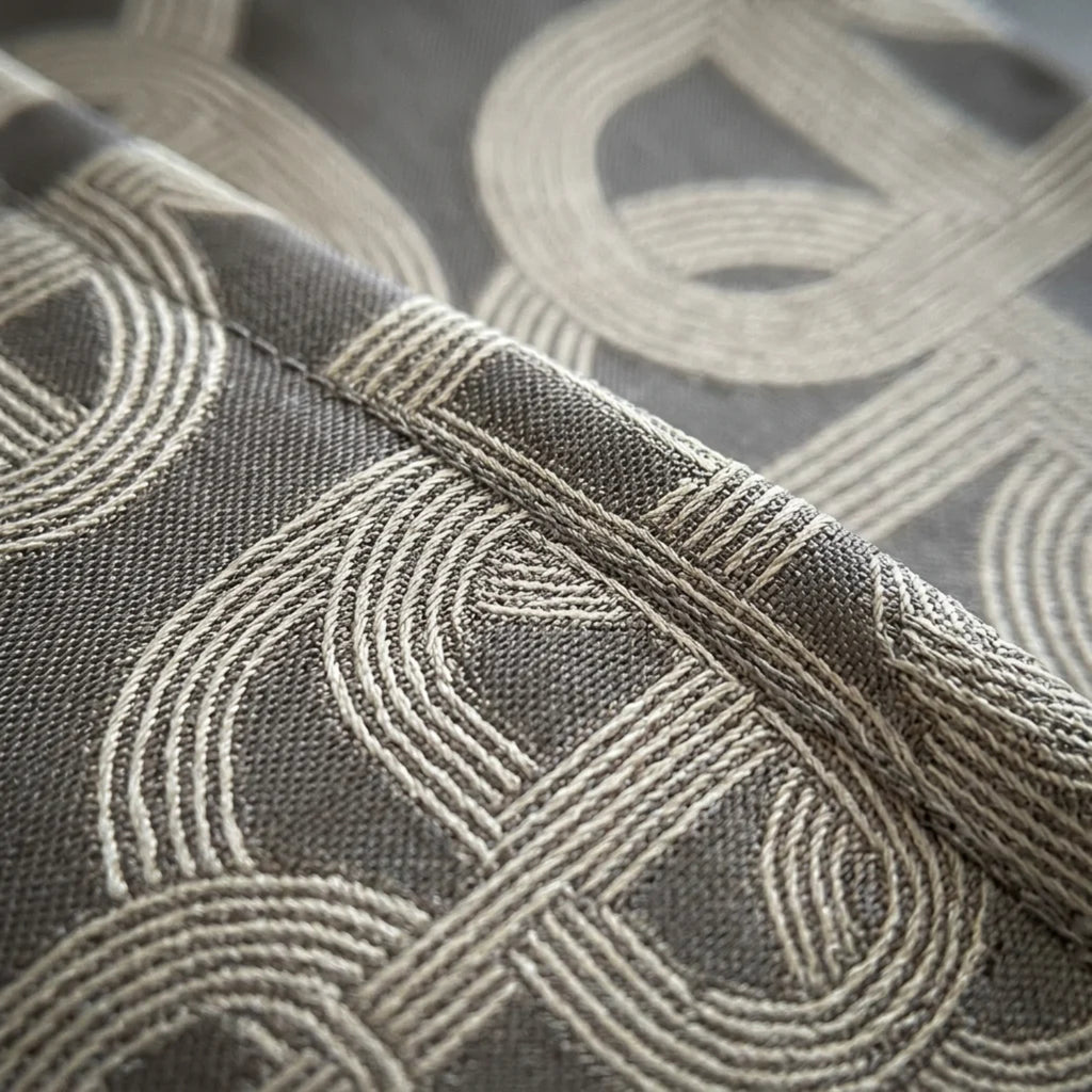 Close-up of a woven fabric with a geometric interlocking circular pattern in taupe and gray.