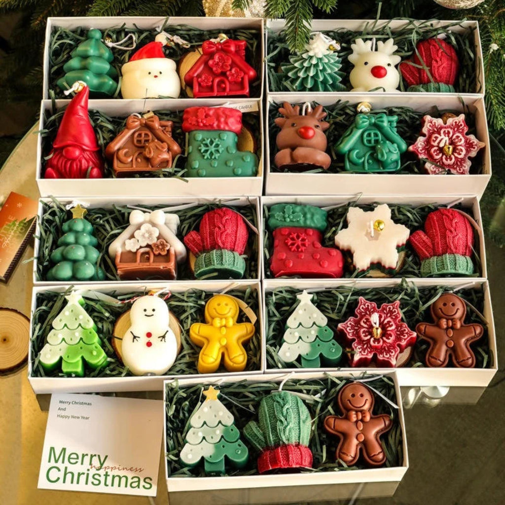 Assorted Christmas-themed candles in a box with a 'Merry Christmas' card.