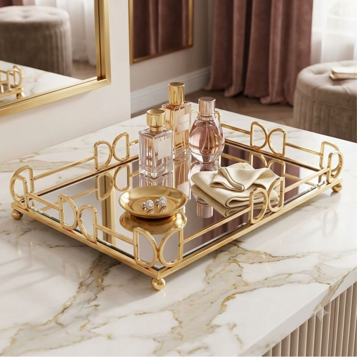 Gold-framed rectangular tray with mirrored glass panels, styled on a white marble surface with perfume bottles, a small gold dish, and folded cream fabric.