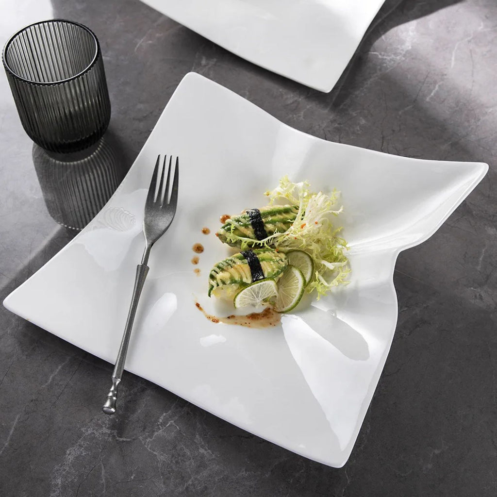 White plate with a dish of food and a fork on a dark surface