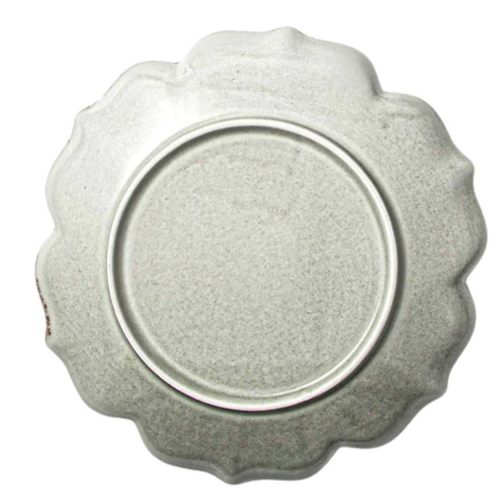 A round, scalloped-edge ceramic plate in a speckled light gray glaze, photographed from directly above on a white background.