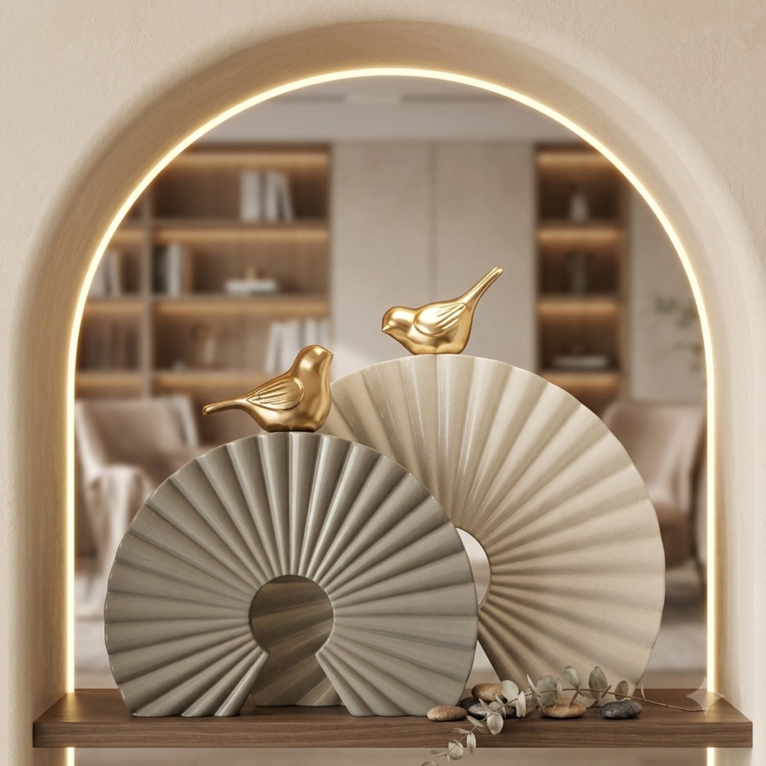 Decorative fan-shaped wall art pieces in warm beige and light gray tones with small gold bird sculptures, displayed on a wooden shelf in front of an arched mirror showing a softly lit interior.