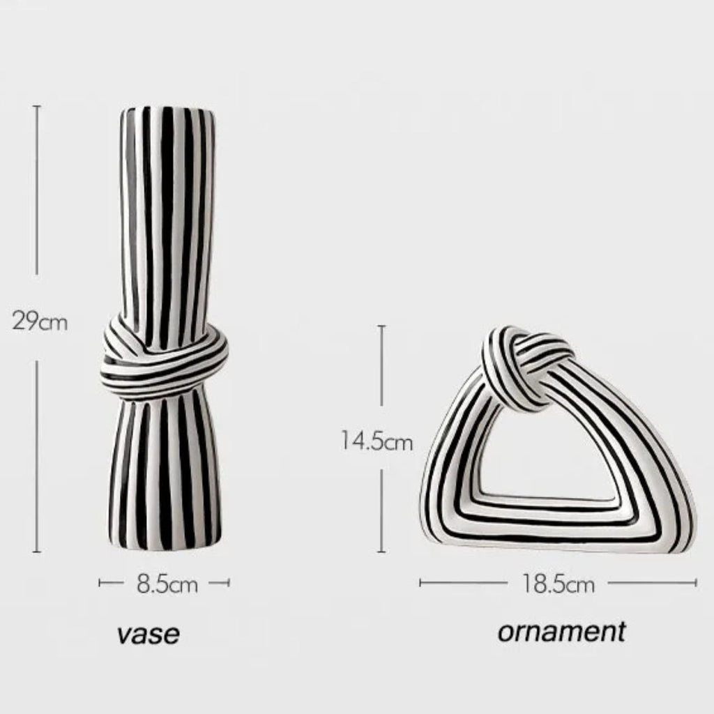Two black and white striped decorative home accessories shown with dimension labels: a cylindrical vase tied at the middle (29 cm tall, 8.5 cm wide) and a triangular knot-shaped ornament (14.