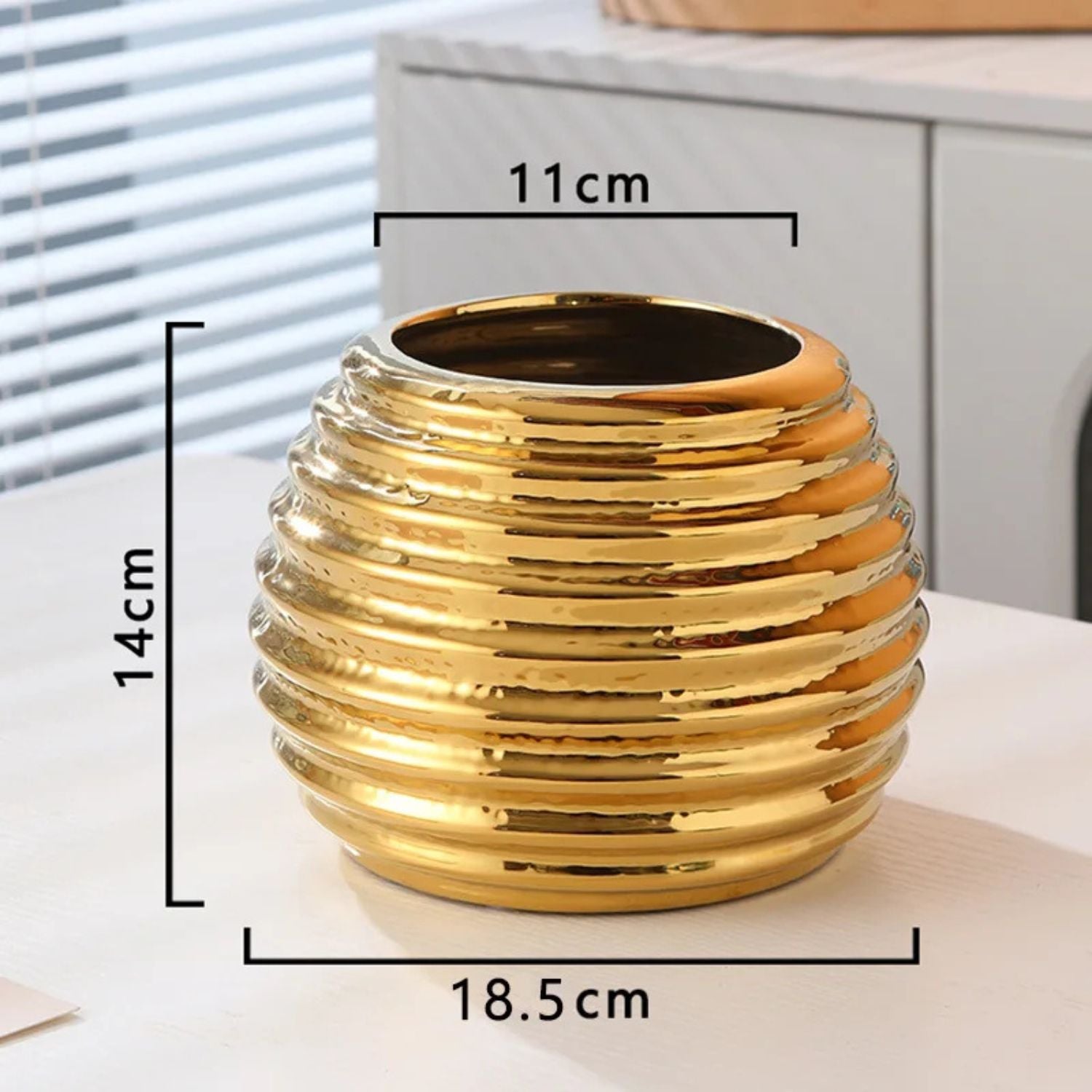 Gold decorative vase with measurements on a neutral background