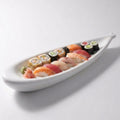 A white ceramic sushi boat platter filled with assorted sushi rolls and nigiri, photographed on a clean light gray studio background.