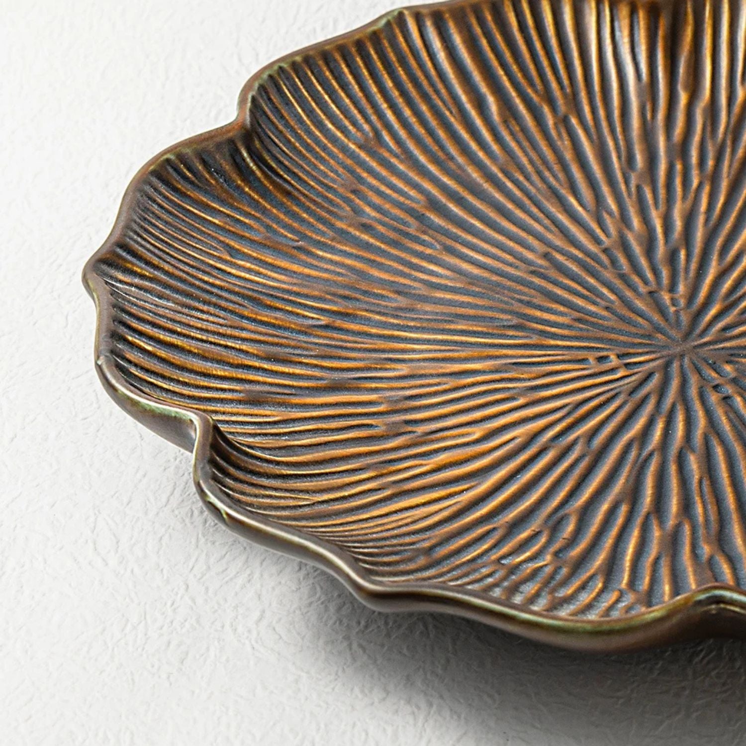 Close-up of a textured bronze leaf-shaped dish on a white background