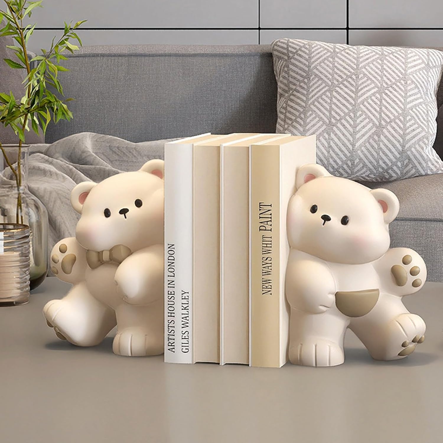 Cream teddy bear bookend set styled on grey surface next to sofa with cushions and candle - books not included