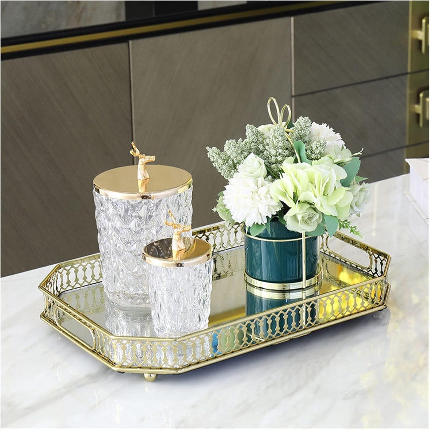 Gold filigree octagonal mirror tray styled on marble kitchen island with crystal jars and teal vase with white flowers