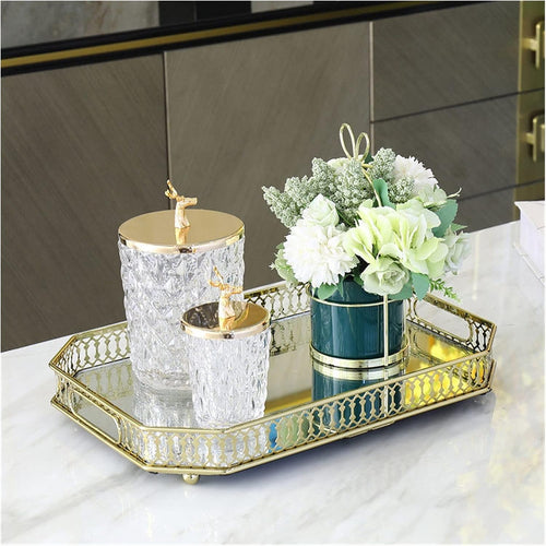 Gold filigree octagonal mirror tray styled on marble kitchen island with crystal jars and teal vase with white flowers