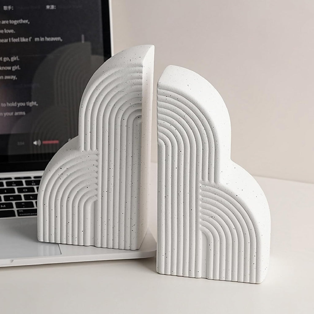 White arch ceramic bookends styled on white desk next to open laptop