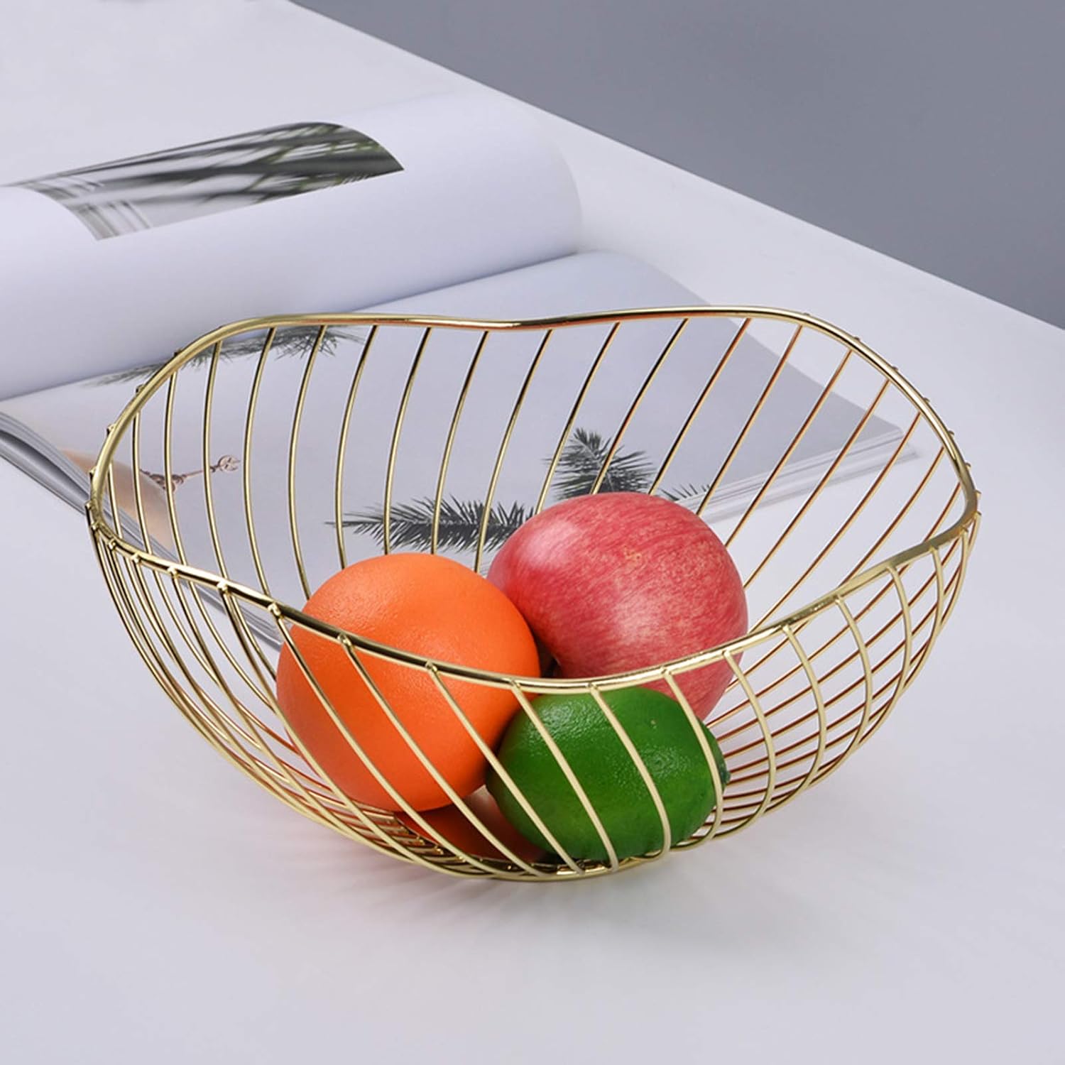 Gold wire metal fruit basket on magazine with citrus fruit