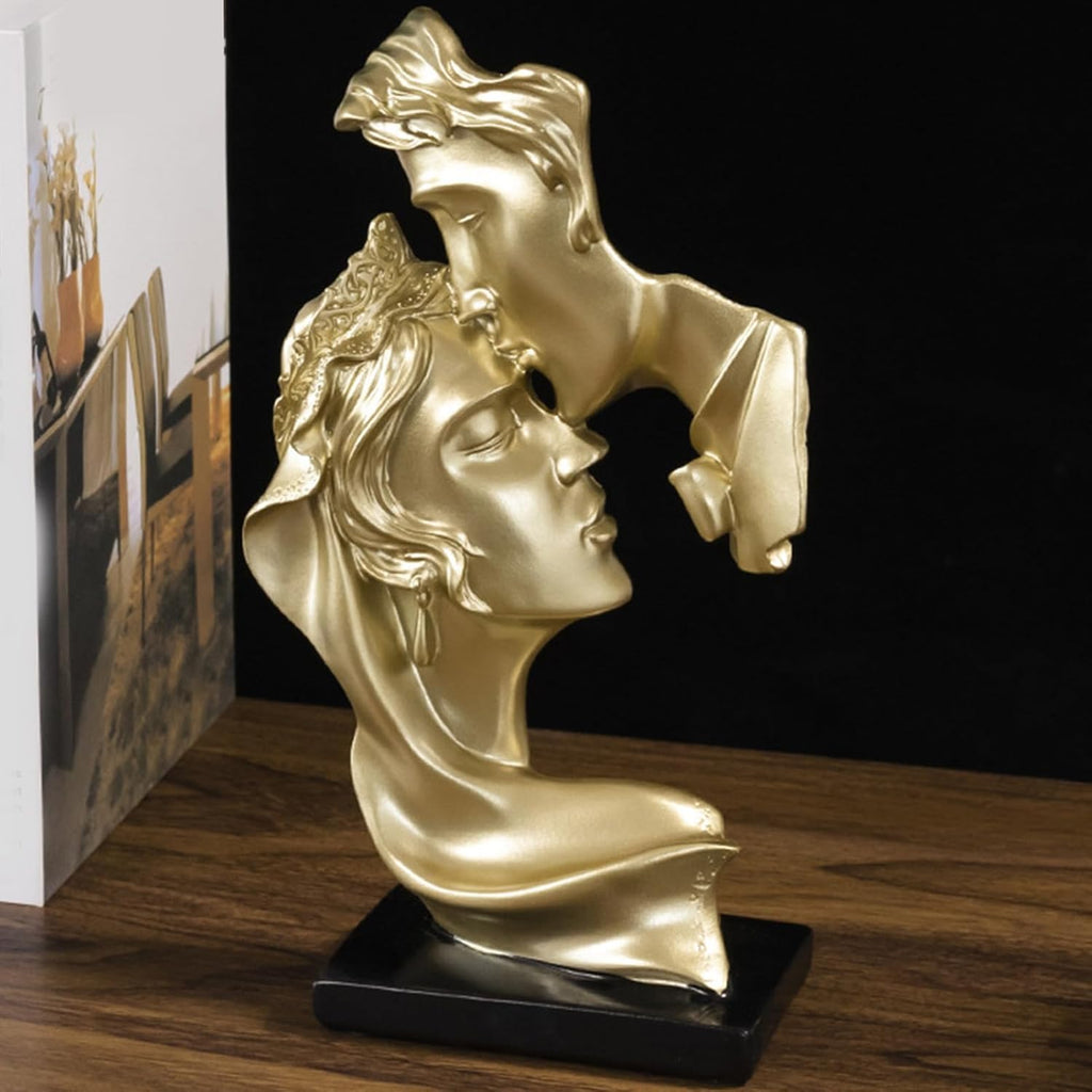 Gold kissing couple forehead sculpture - side view showing flowing hair and draped fabric detail on dark background