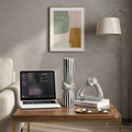 A styled interior scene showing a wooden coffee table with a laptop, two black-and-white striped decorative vases, a sculptural object on stacked books, and a textured gray wall behind. No person is present, but this is not a clean isolated product shot because it is set in a real room environment, so subject_type is Lifestyle.