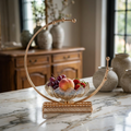 Gold C-shape crescent fruit bowl styled on marble kitchen island with fresh fruits