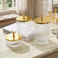 Set of 3 ribbed glass storage jars with gold stag lids styled on marble vanity with perfume bottles