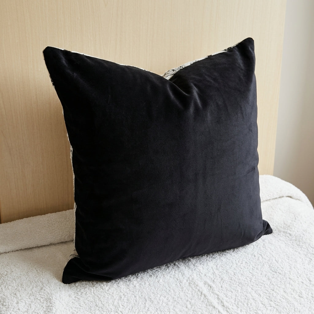 Black and cream abstract geometric cushion styled on a table in a bright living room