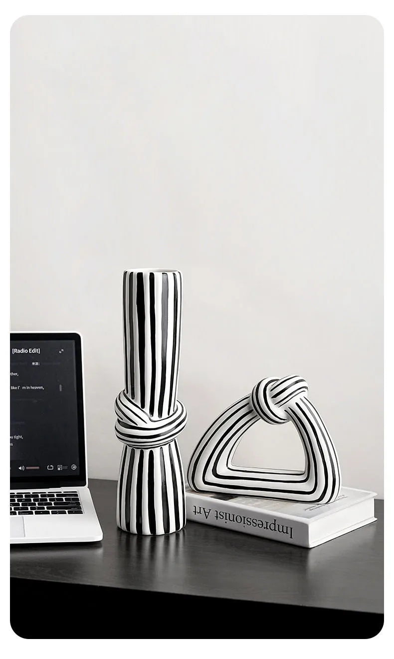 Black and white striped knot vase and ornament set styled together on dark desk with laptop