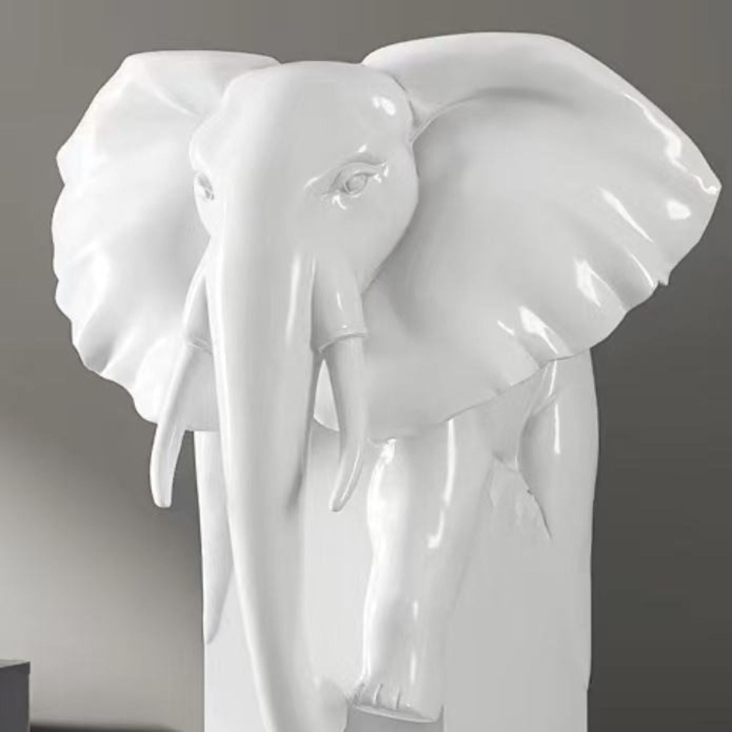 A glossy white elephant sculpture with large ears and long tusks, shown against a dark gray background.