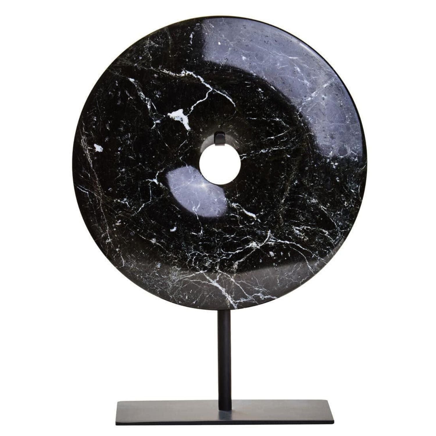 A round black stone donut sculpture with white marble veining, displayed on a minimalist black metal stand against a solid white background.