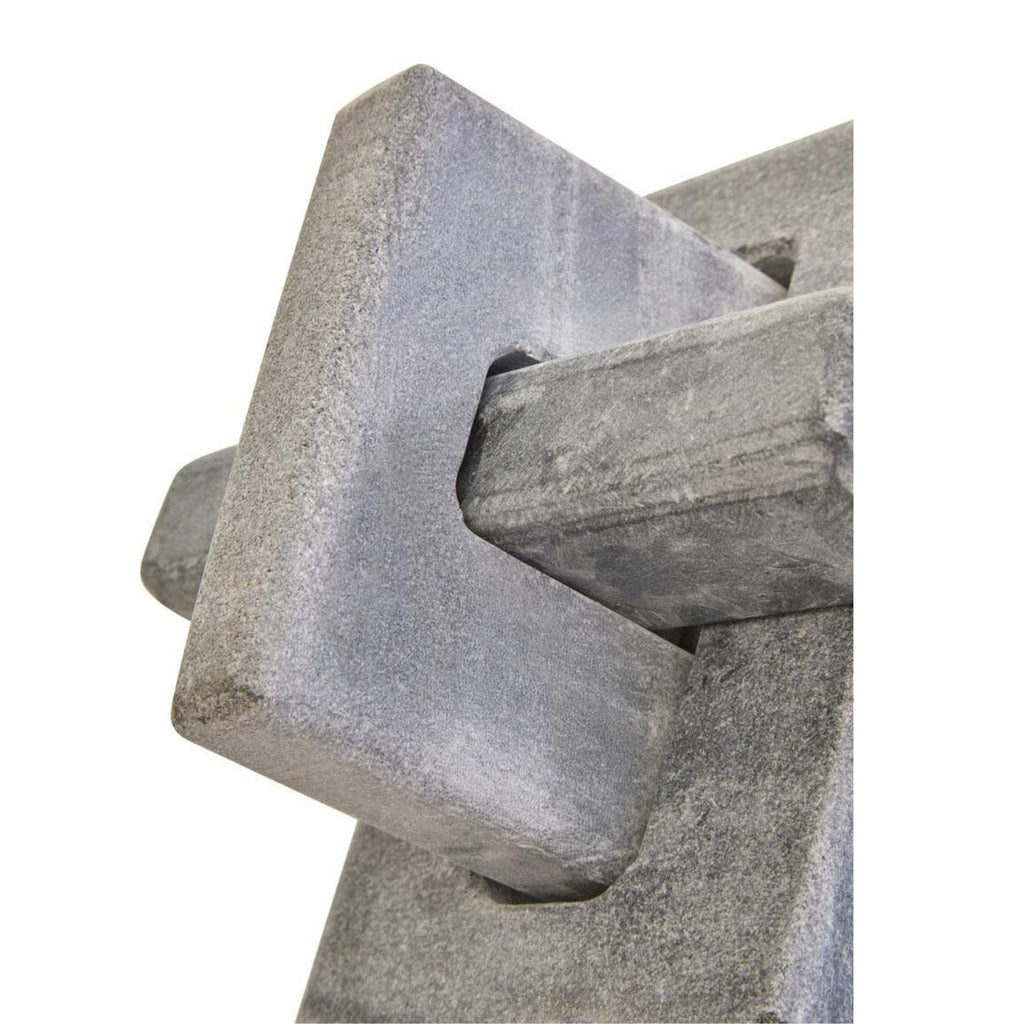 A close-up of a gray stone or concrete decorative wall feature with a textured, rough-hewn geometric design on a white background.