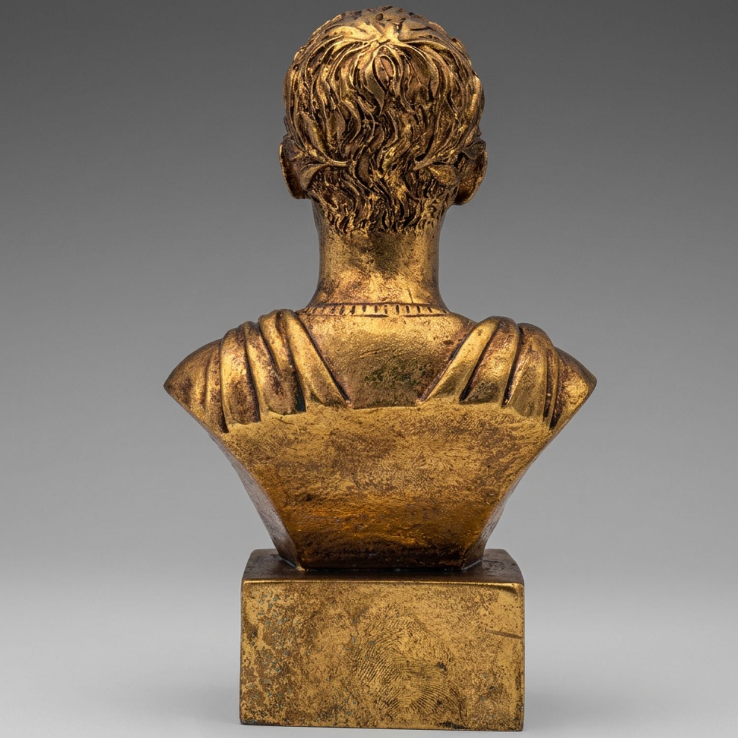 A classical-style bronze bust sculpture shown from the back, mounted on a rectangular pedestal base against a neutral gray gradient background.