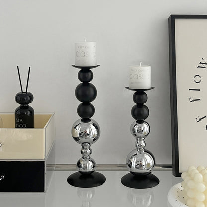 Black and chrome ball candle holders styled with white pillar candles on a white surface
