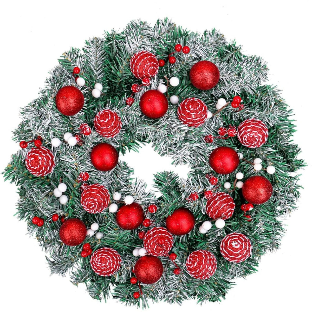 A festive Christmas wreath made of green artificial pine branches with a light silver-white snow dusting, decorated with shiny red ornaments, white berries, and textured red pinecones, isolated on a white background.