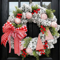 A festive flocked Christmas wreath hanging on a black front door, decorated with green pine branches, red berries, striped candy cane ornaments, red-and-white gingham ribbon bows, and small red-and-white gingham triangle flags.
