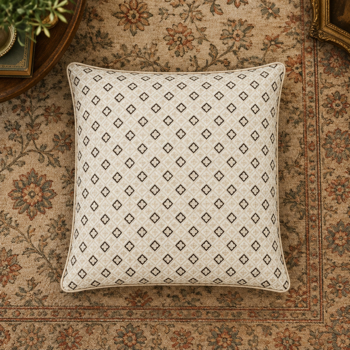 A square throw pillow with a beige and brown geometric diamond pattern, styled on a vintage floral area rug.