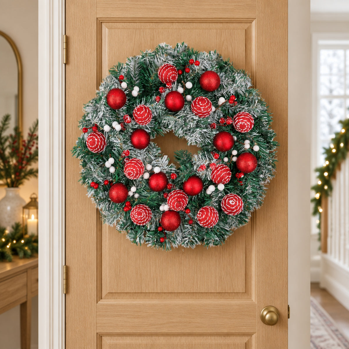 A festive Christmas wreath with red ornaments, red pinecones, and white berries, hung on a light wood front door.