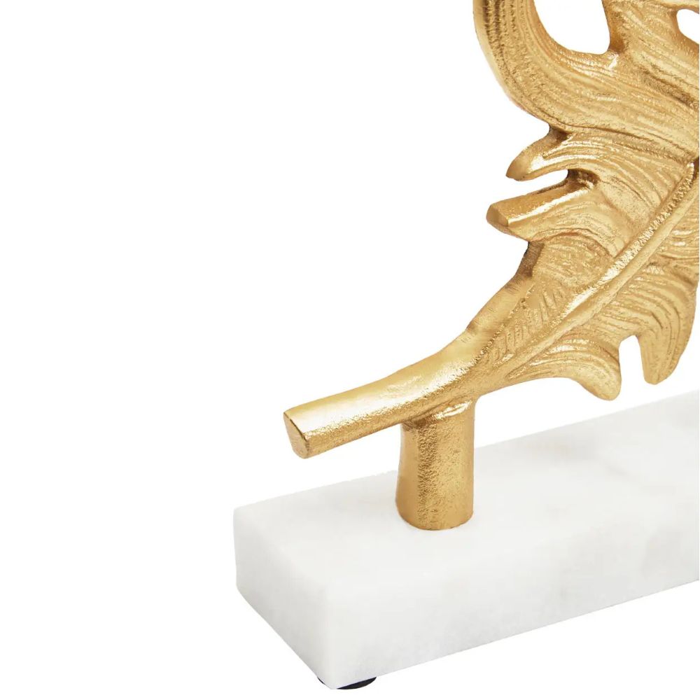 Close-up of marble base and gold stem of peacock feather sculpture
