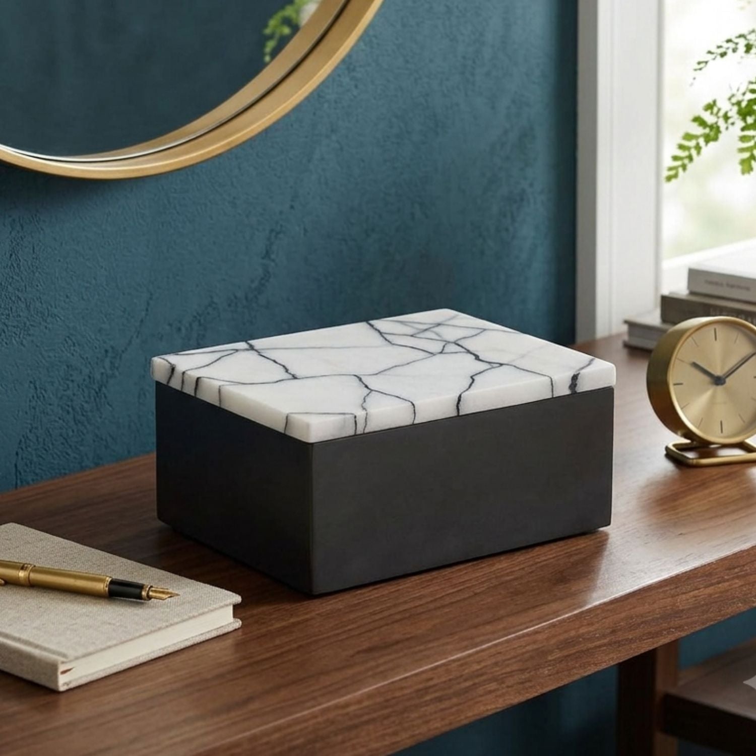 A rectangular storage box with a white marble-patterned lid and a matte black base, styled on a wooden desk in a home interior setting.