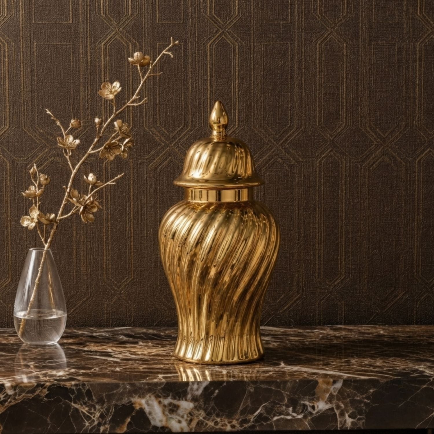 A metallic gold decorative jar with a ribbed, fluted body and a matching lid, displayed on a dark marble surface against a dark brown patterned wallpaper background.