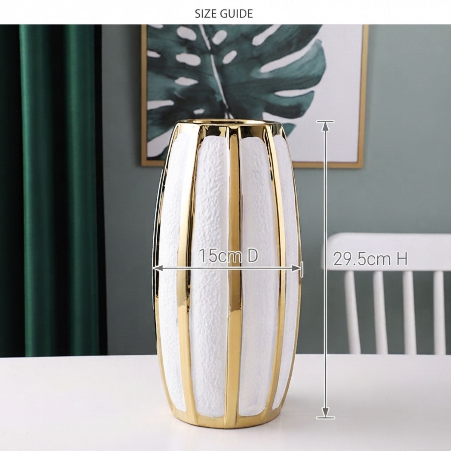 A tall cylindrical vase with a white textured body and polished gold vertical bands, shown on a tabletop in a styled interior. White measurement lines and text indicate dimensions: 15cm diameter and 29.
