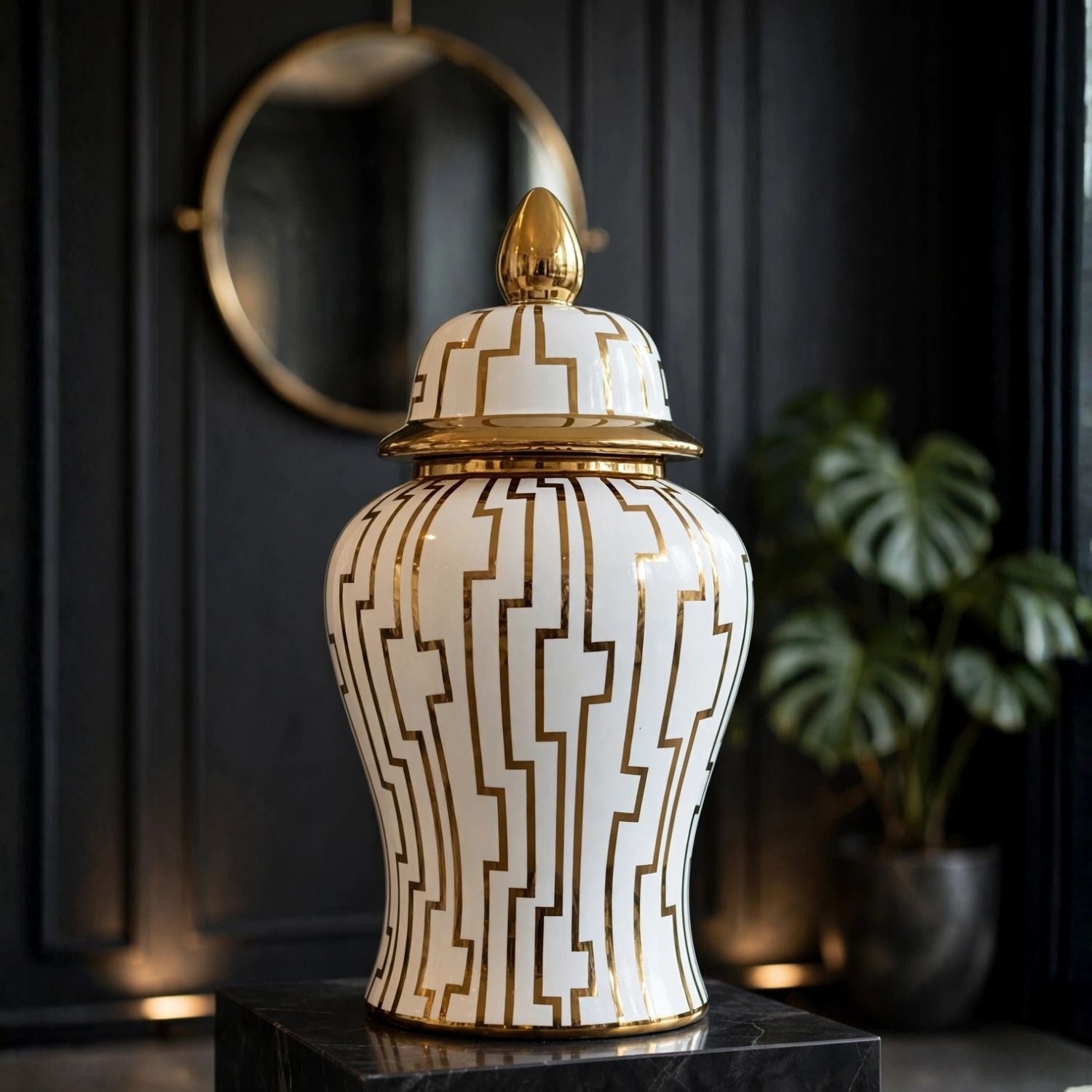 A white ceramic ginger jar with a lid, decorated with a gold geometric pattern and gold trim, displayed on a black marble pedestal in a dark interior setting.