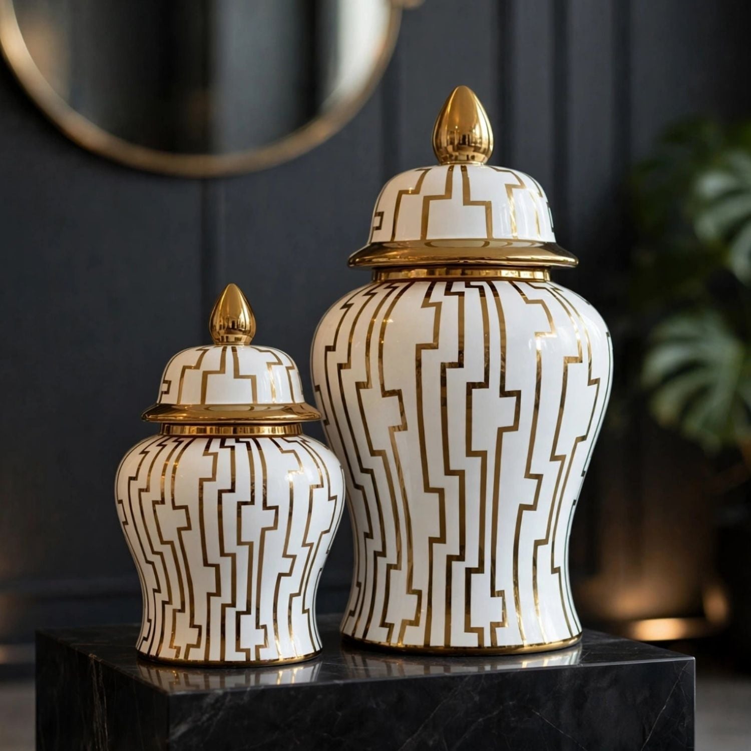 Two decorative lidded ginger jars with a white and gold geometric pattern, displayed on a black marble pedestal in an elegant interior setting.