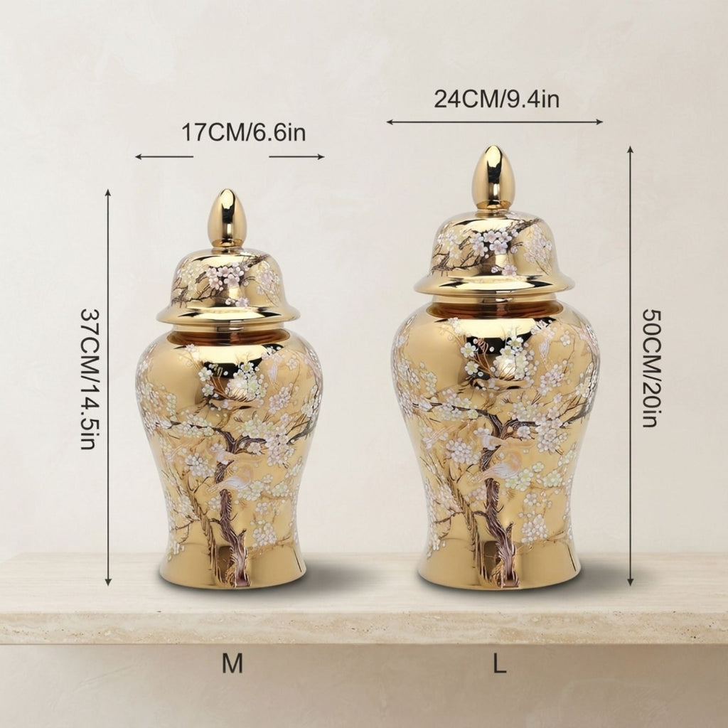 Two decorative gold-toned urns with floral painted detailing, shown on a light surface with overlaid size measurements labeled M and L.