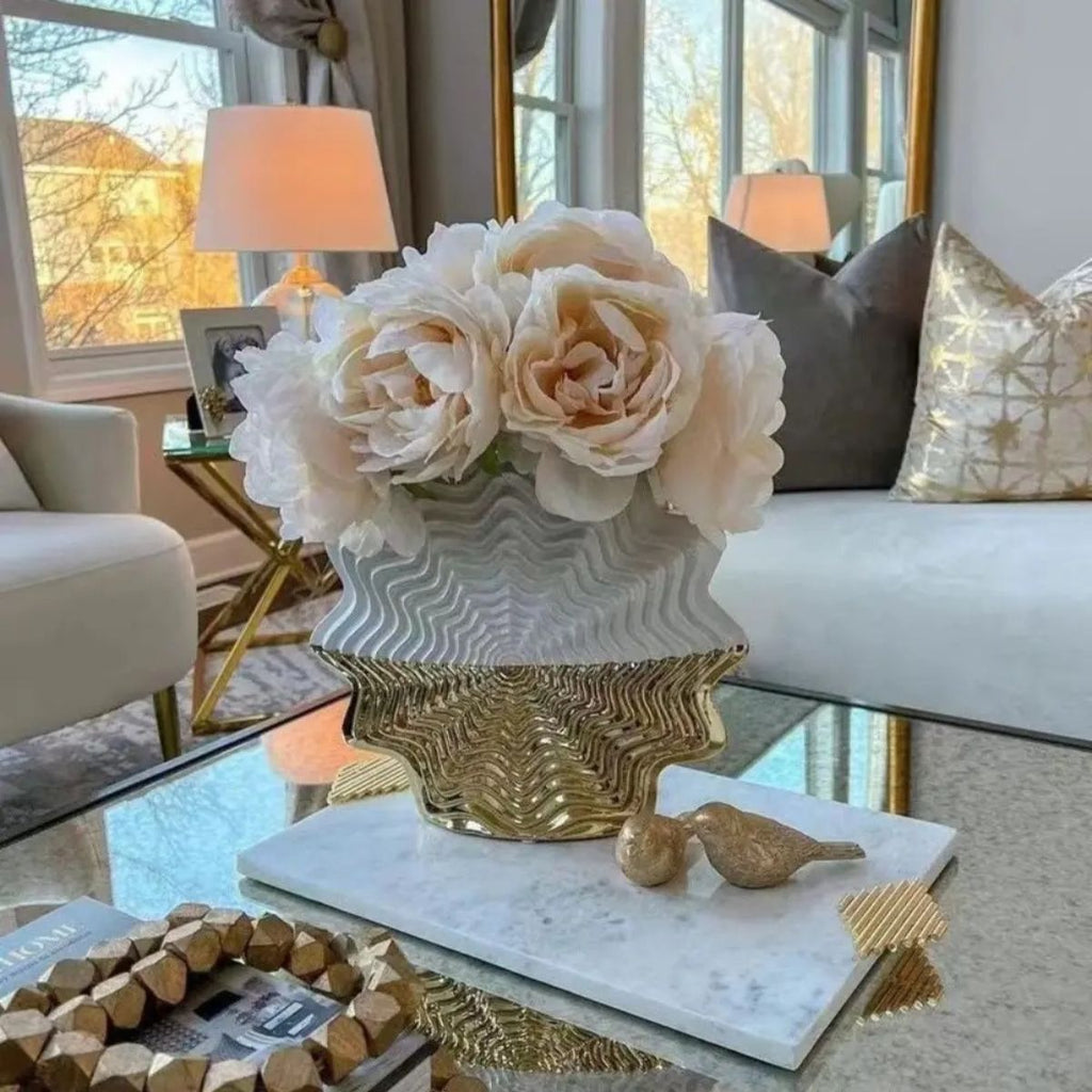 White and gold ceramic vase with white floral arrangement on coffee table