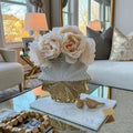 White and gold ceramic vase with white floral arrangement on coffee table
