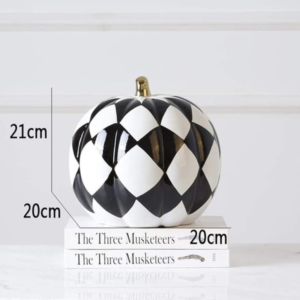 Glossy black and white harlequin pumpkin ornament with gold stem