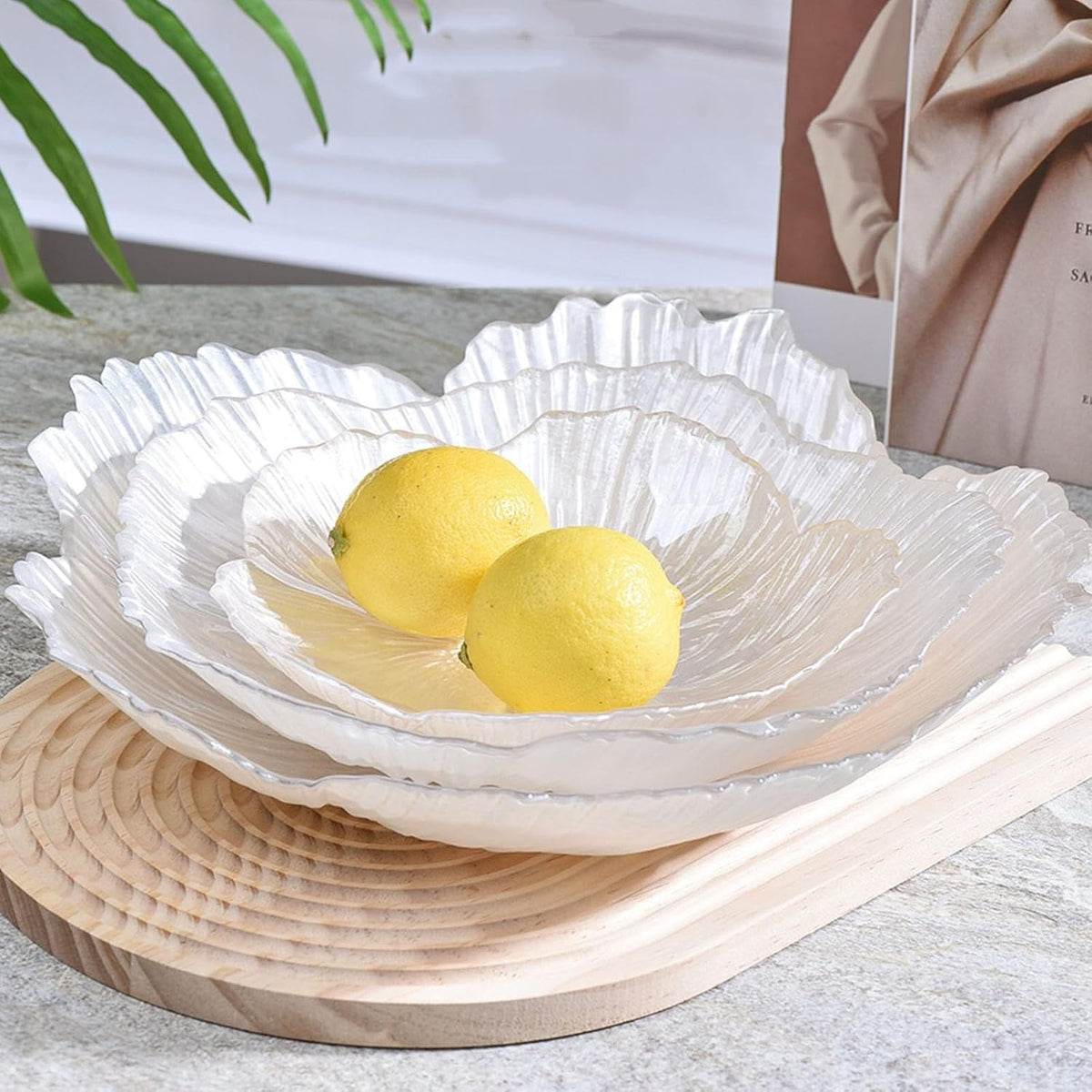Three translucent crystal glass fruit plates styled with lemons on a dining table