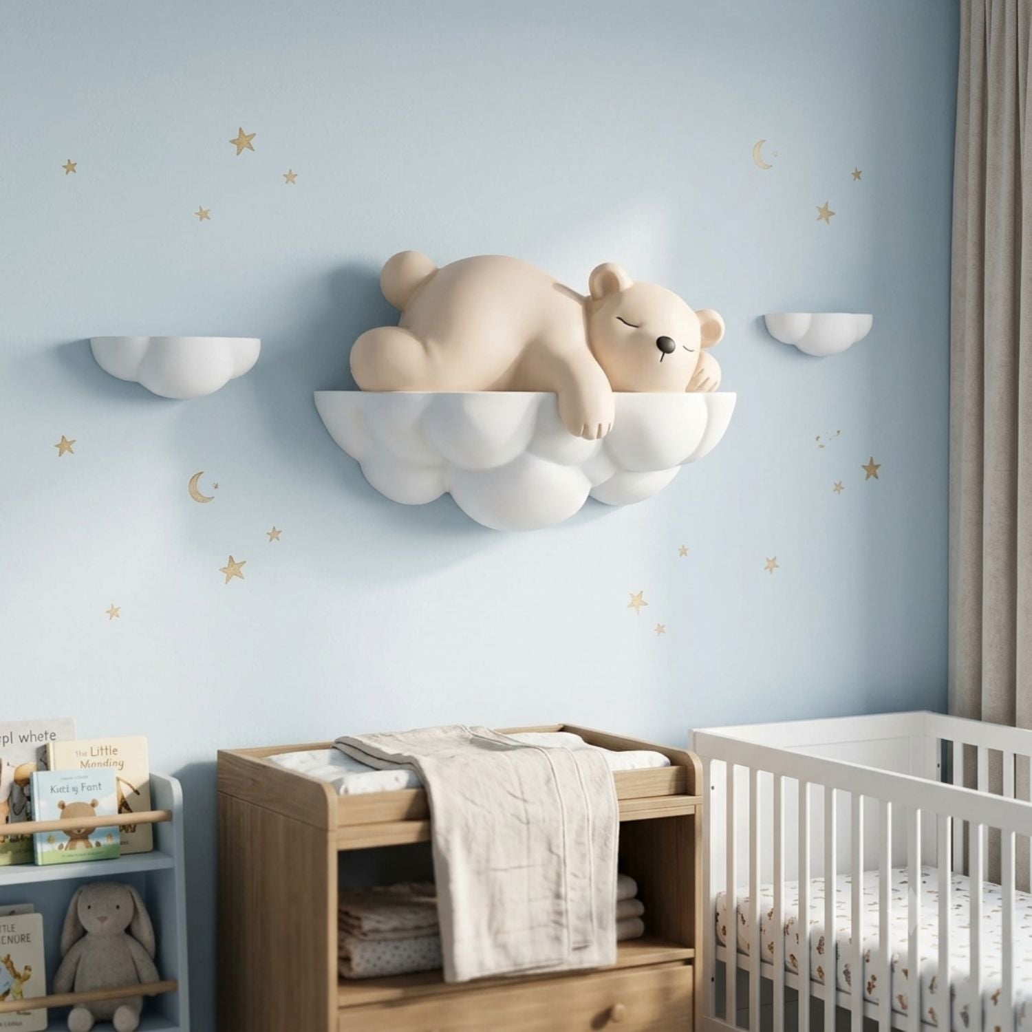 A nursery room scene with a beige sleeping bear figure displayed on a white cloud-shaped wall shelf, alongside matching cloud and moon wall decals, a wooden changing table, and a white crib against a light blue wall.