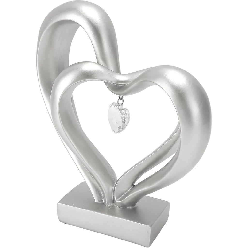 A silver-toned decorative heart sculpture with two interlocking heart shapes and a small clear heart pendant, displayed on a rectangular base against a plain white background.