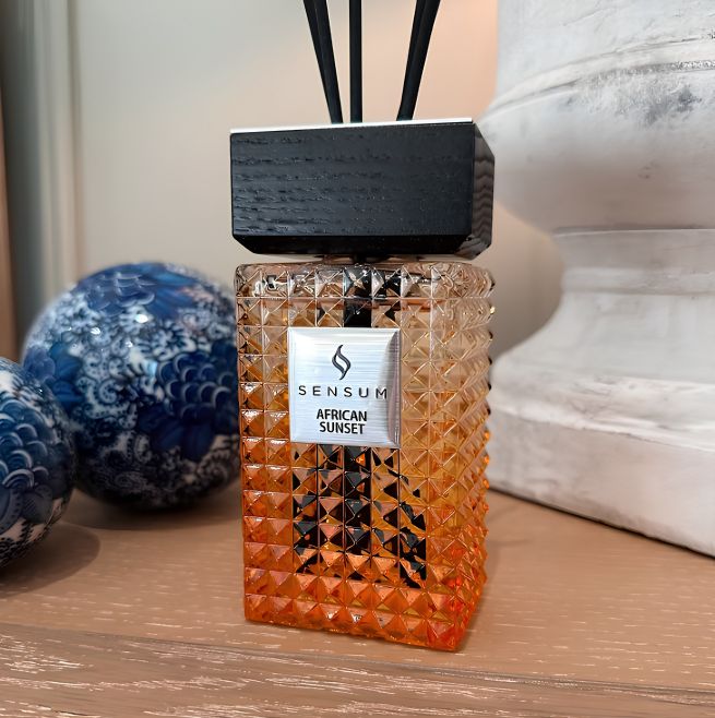 Sensum African Sunset Reed Diffuser next to a black and white vase