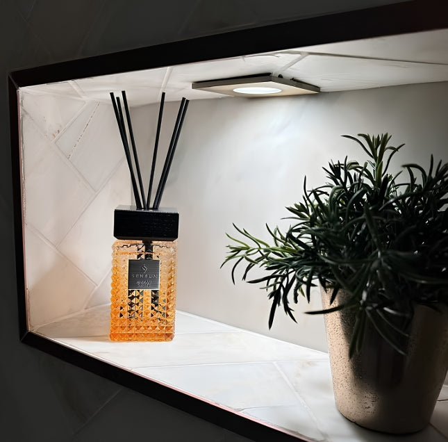 Sensum African Sunset Reed Diffuser in a lit bathroom niche