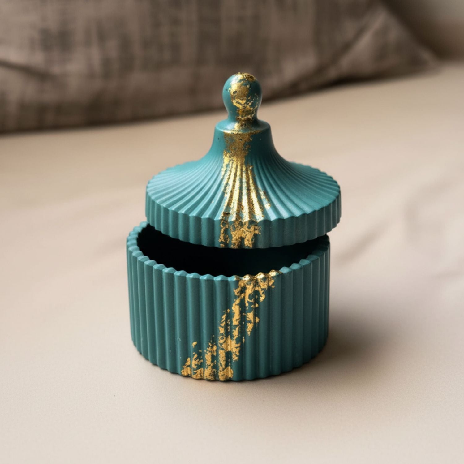 Teal decorative box with gold accents on a beige surface